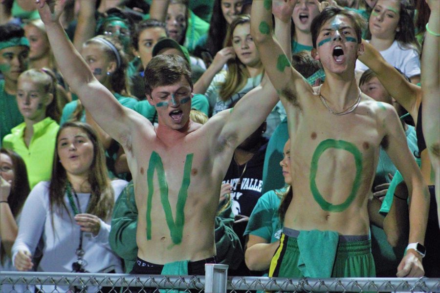 Seniors on frontline, Ben Decker and Jack Angell, cheer animatedly during the football game against hometown rival, Bettendorf, effectively getting others in the student section energized. 