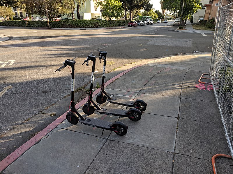 Three bird scooters available for use on the sidewalk.