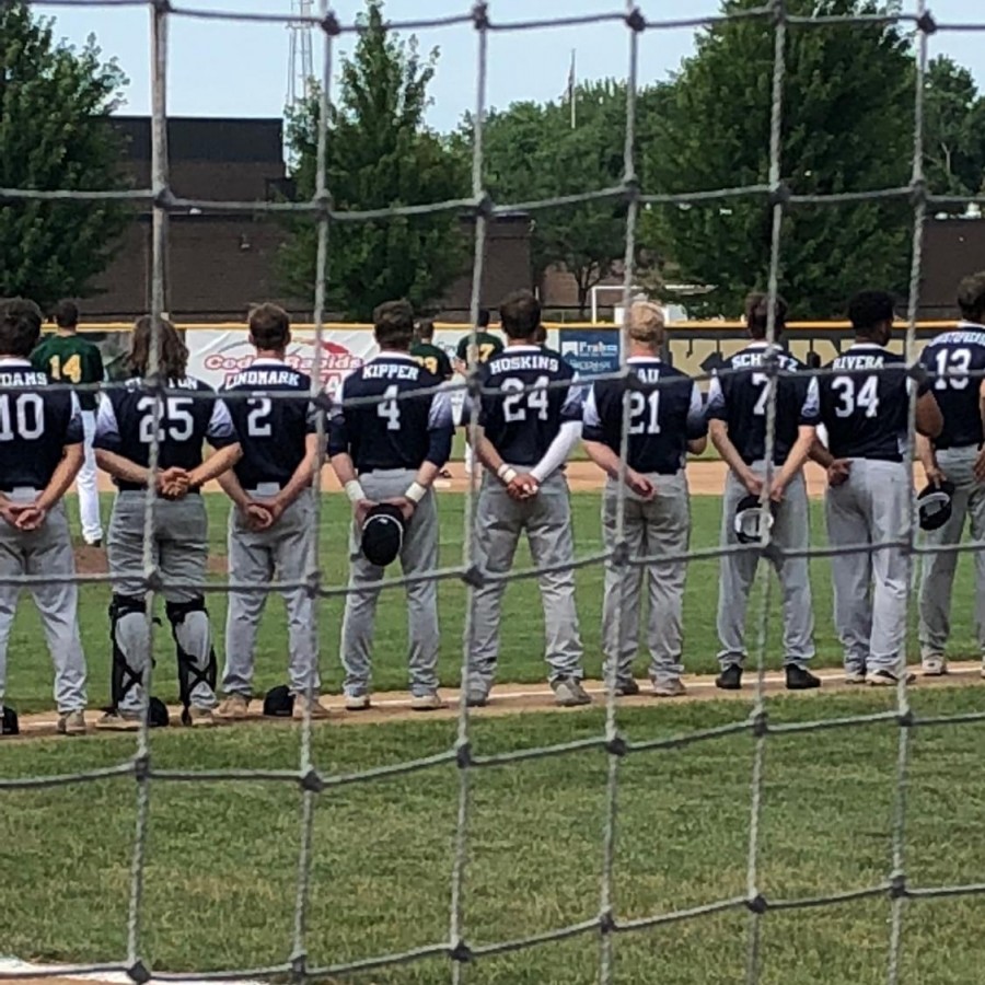 Pleasant Valley Baseball team standings for the national anthem before playing in the hot, summer heat.
