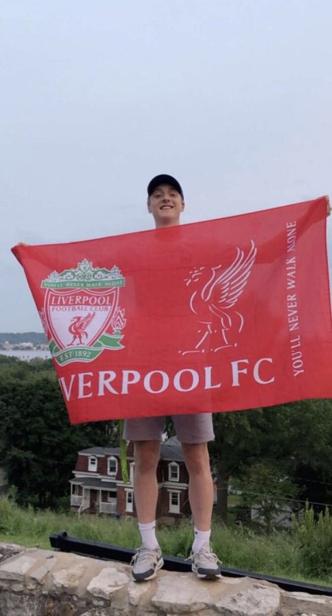 Spencer Brecht holding the flag of his favorite EPL team, Liverpool.