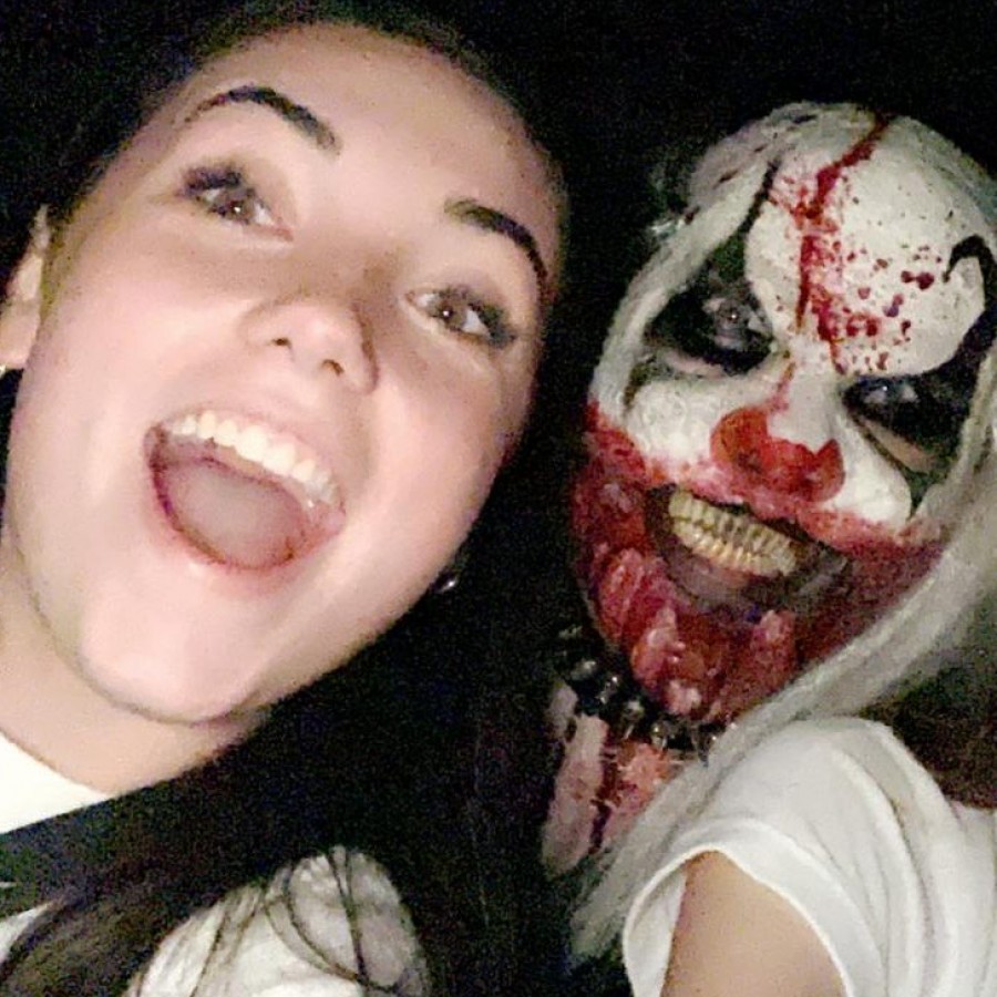 Senior Caitlin Crome and her friend pose with an actor at a local haunted house. While the actor’s mask is terrifying, the two know they are in no real danger. 