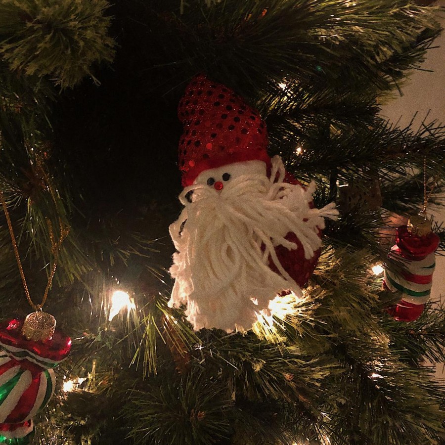 A Santa-themed ornament hangs from a Christmas tree.