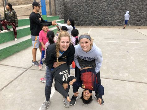 Seniors Kayla Nutt (left) and Addie Even (right) pose for a playful picture with their two new Peruvian friends, displaying their love for volunteering around the world.