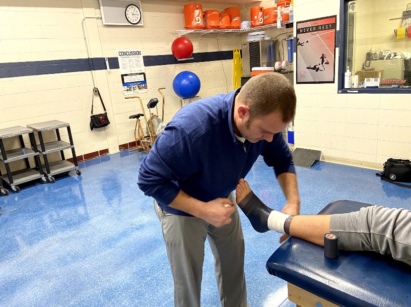Jason Viel tapes up freshman Rusty VanWetzinga’s ankle before his wrestling practice.