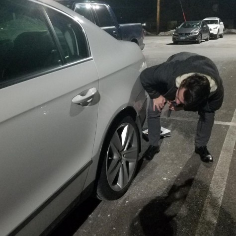 Senior Bradley Hamilton inspects one of his cars wheels well for accumulated salt.
