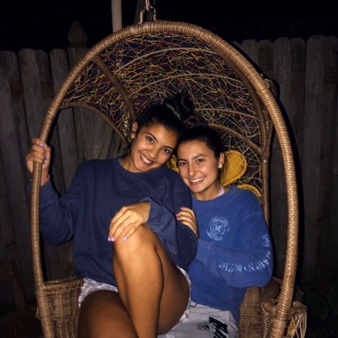 Lifetime lovers and seniors Cienna Pangan and Kate Stewart sit in a hanging chair together.