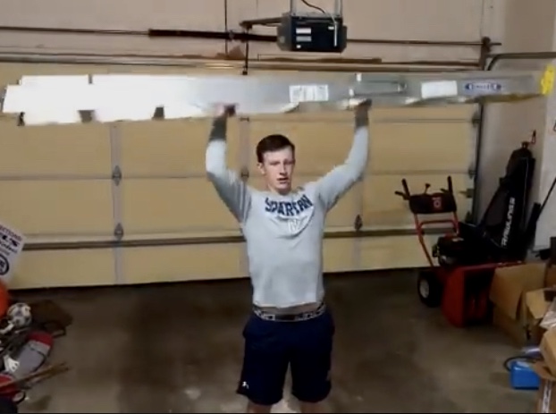 Freshman Barrett Lindmark uses a ladder to do military presses.