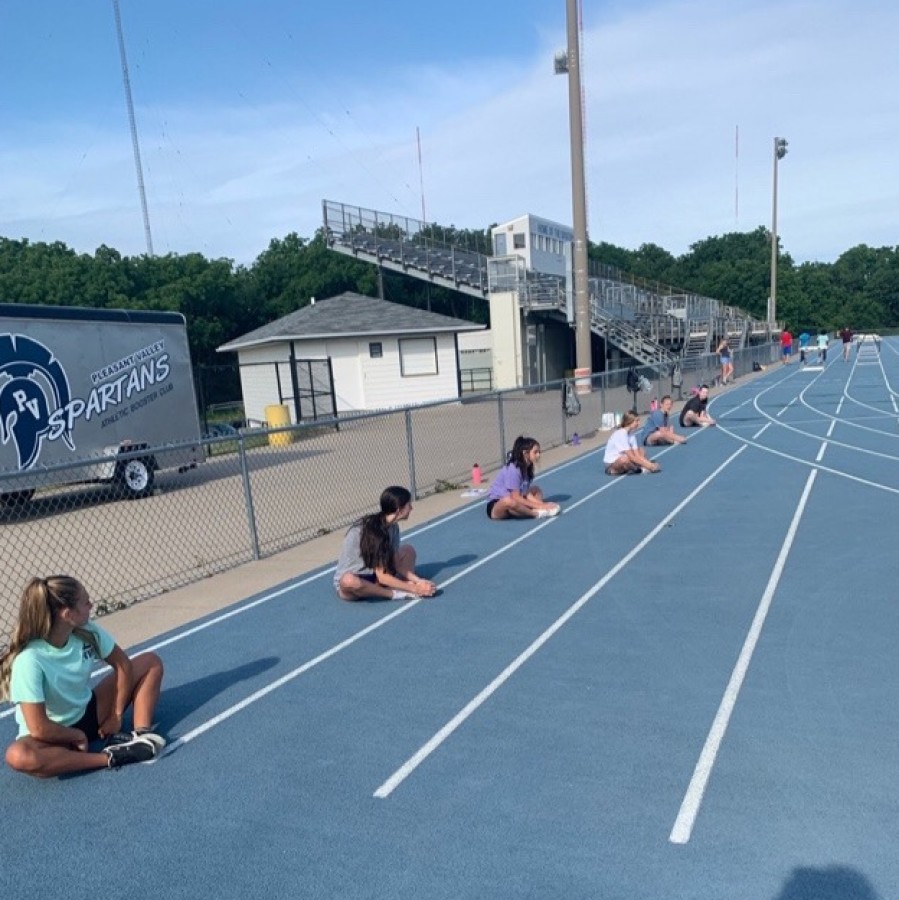 A group of cheerleaders stretch socially distanced at their outdoor practice.