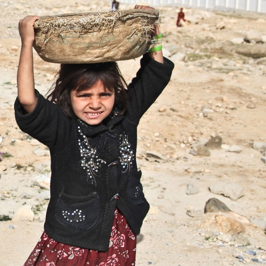 An impoverished, school-age female of a developing country does arduous labor in the fields to support her family while schools remain closed. 