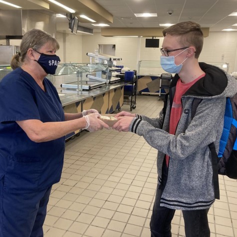 Food service worker Robin Funk hands gluten-free and dairy-free food to senior Jonathan Sulgrove.