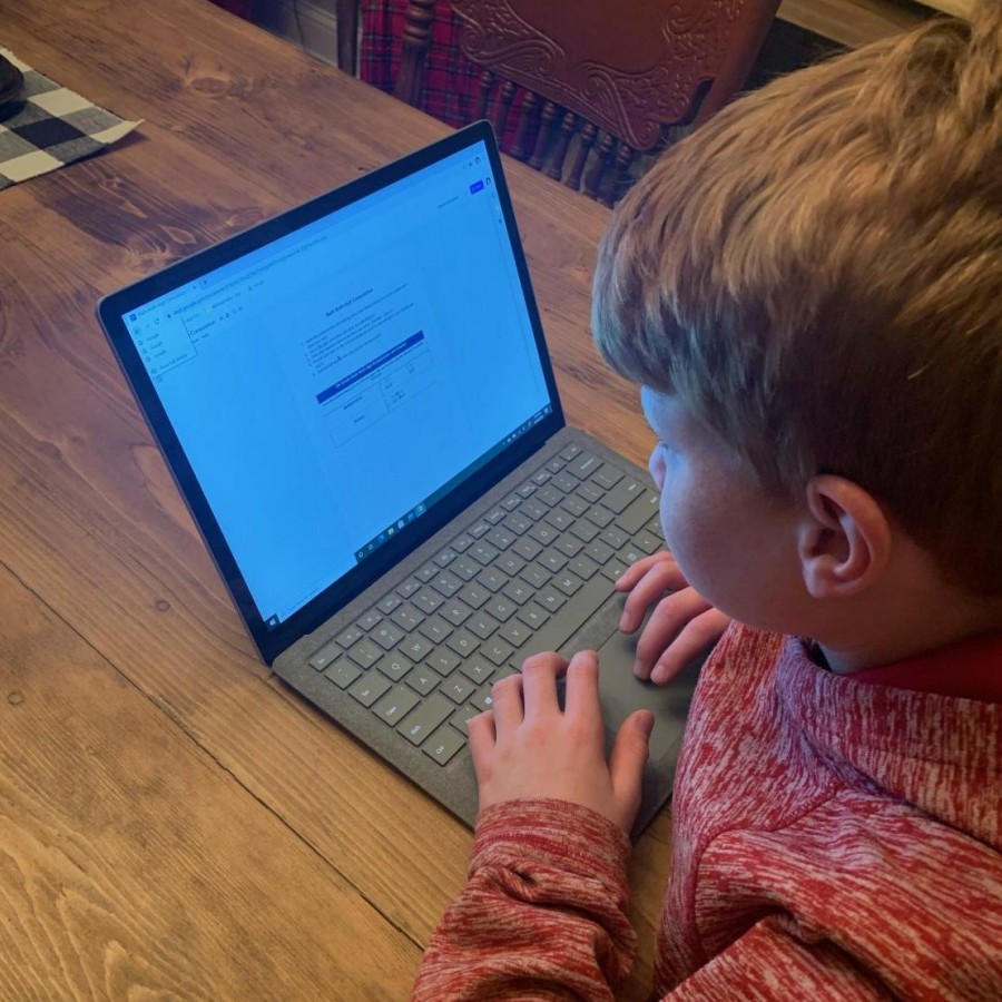 Elementary student Mitchell Holst attempts to solve a challenging math problem at home, hoping he is able to submit it without the interference of internet issues.