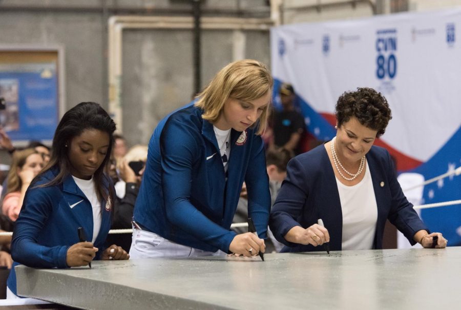 Simone Biles signs the steel plate signifying the beginning of construction of the U.S embassy.