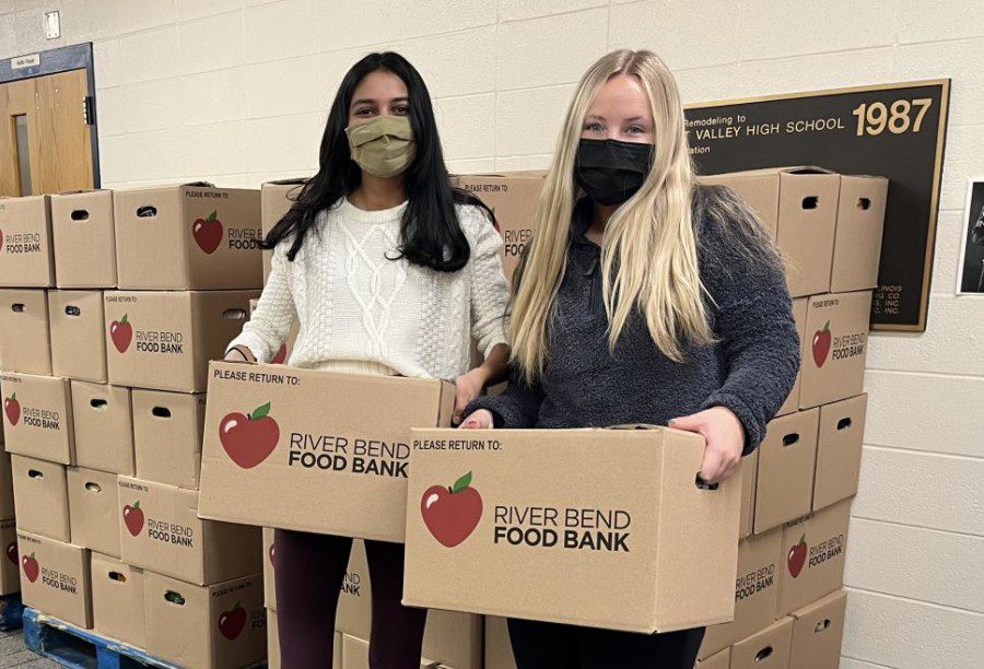 Shobini Iyer and Jillian Keppy pose in front of thousands of pounds of cans donated by students and community members for the annual SHD.