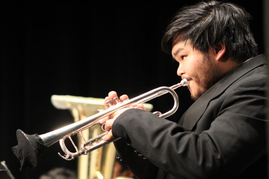 Senior Luke Wang watches the director attentively as he plays the trumpet during the Wind Ensembles Winter Concert on Feb. 14.