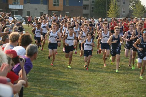The Pleasant Valley Boys Cross Country Freshman-Sophomore team darts off the start line together as spectators cheer on.

