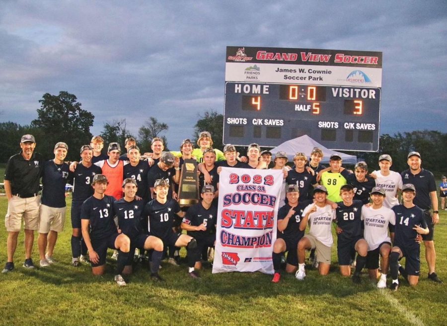 The Pleasant Valley Spartans boys soccer team poses in front of the scoreboard after defeating Waukee Northwest in the 3A state championship.