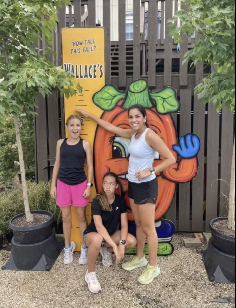 Sophia Foad, Lexi Minard and Maddie Millage pose in front of a pumpkin sign at Wallace’s Garden Center. 