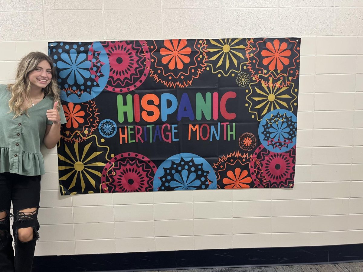 Senior Cassi Paustian poses next to a poster in the language hallway where she took 4 years of Spanish. 

