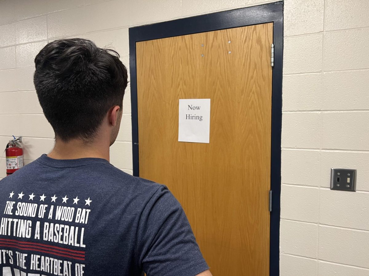  PV student looking at Now Hiring sign posted on a door
