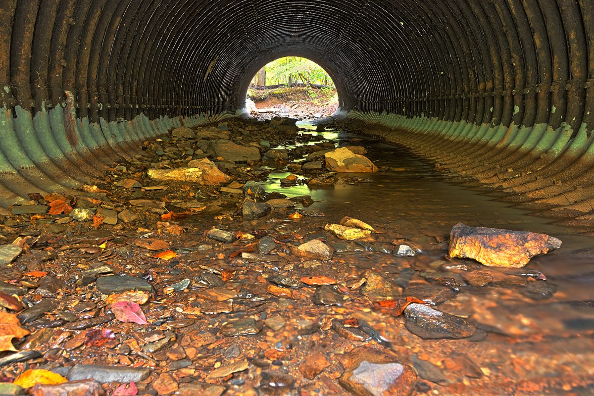 A water passage is pictured filled with garbage, particularly plastic, which is known to leave traces of PFAs after prolonged submersal. Photo credit to Nicolas Raymond.
