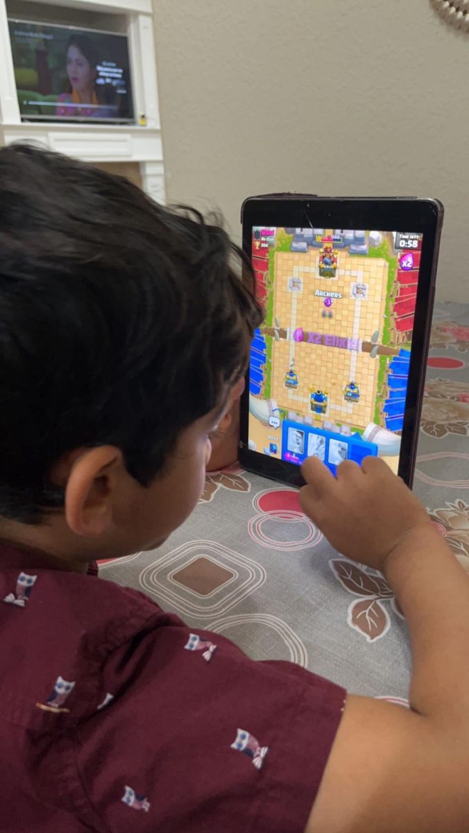 Young child playing on iPad , being one of many who are reliant on their screens for entertainment and discipline