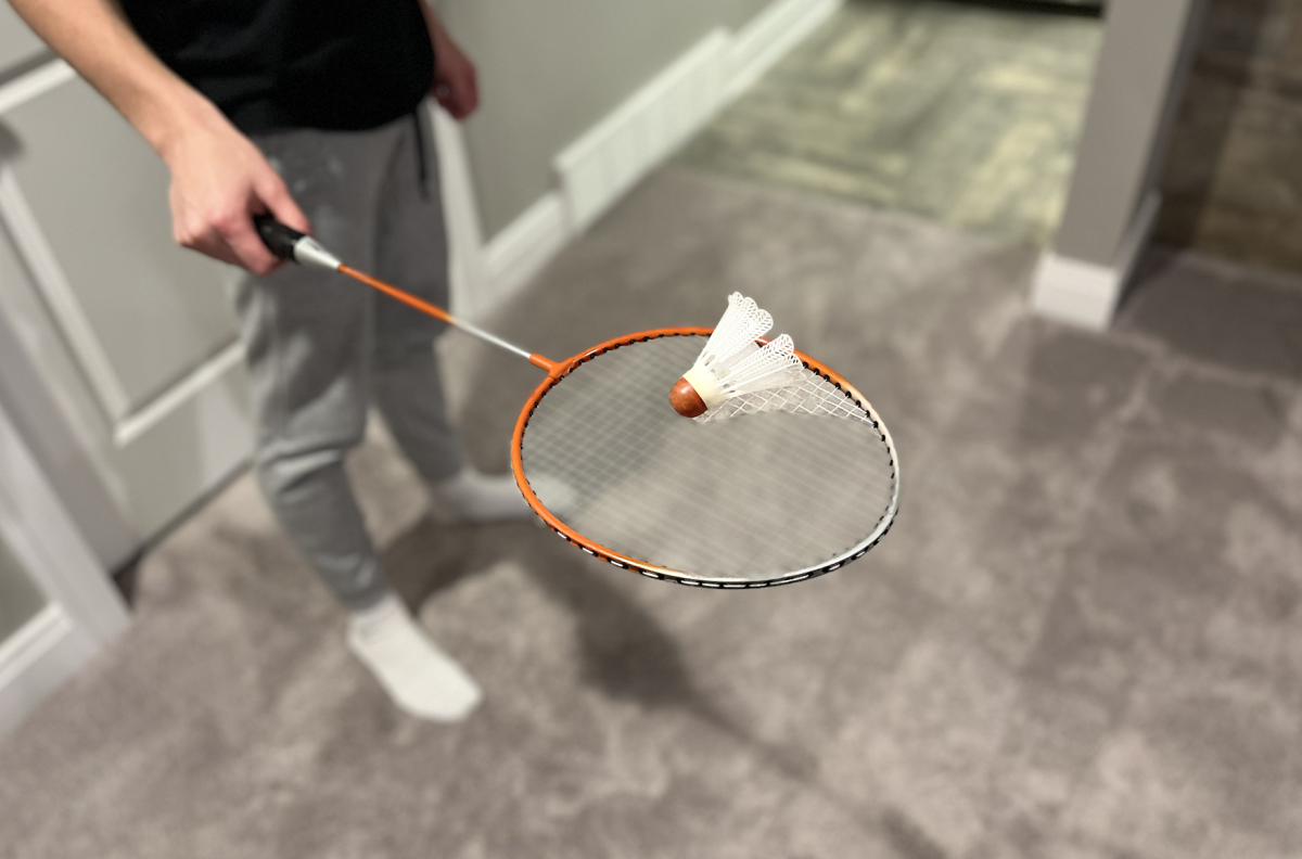 Student holds a badminton racket with a birdie balanced atop.
