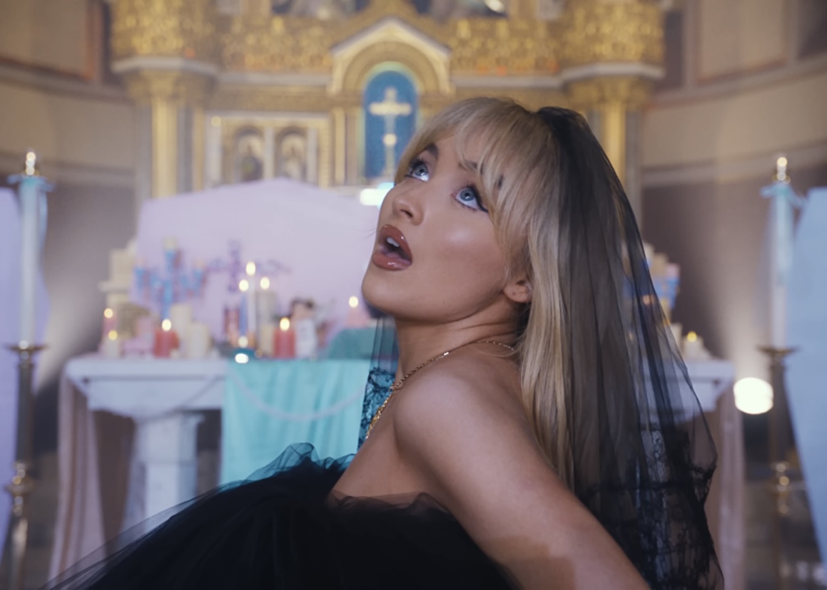A still shot from Carpenters music video for Feather, directed by Mia Barnes. Posing in front of an altar in a real Catholic church, the video has spurred relgious controversy.