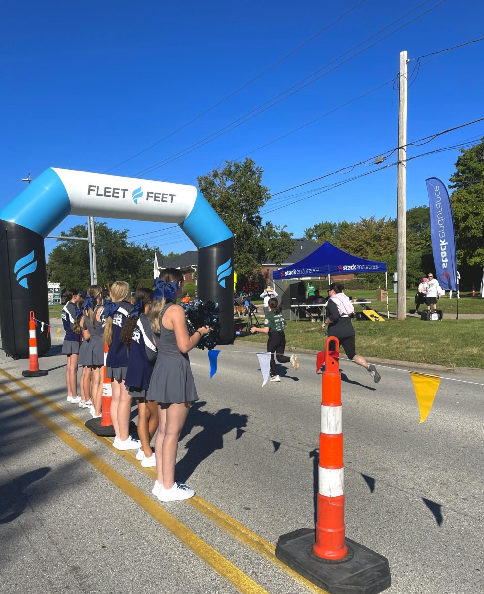 Pleasant Valley cheerleaders gather at the finish line supporting runners completing the 5k race. Their involvement in this community event heightens the energy and motivates the runners.