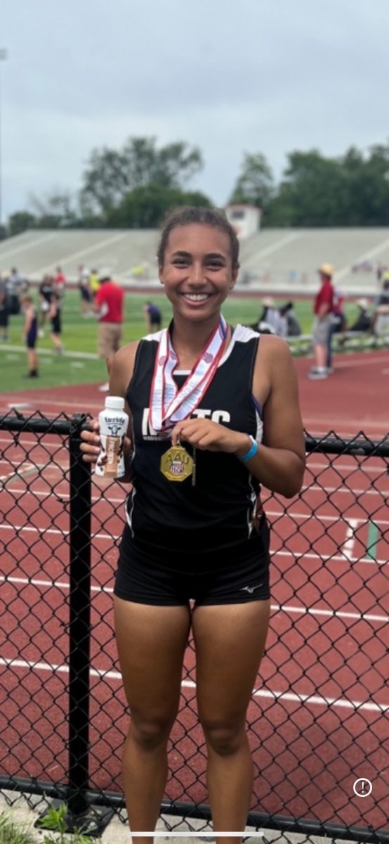 Discus thrower Gabi Ragins smiles with medal after receiving first place in discus and second place in javelin at the Des Moines AAU District track and field meet. Photo Credit: Jaime Ragins