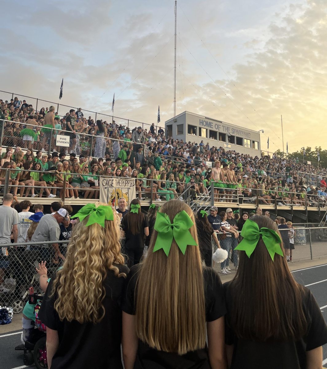 Pleasant Valley Platinum dancers don signature green bows along with greened out PV student section in support of greenout tradition at the Bettendorf-Pleasant Valley football game.