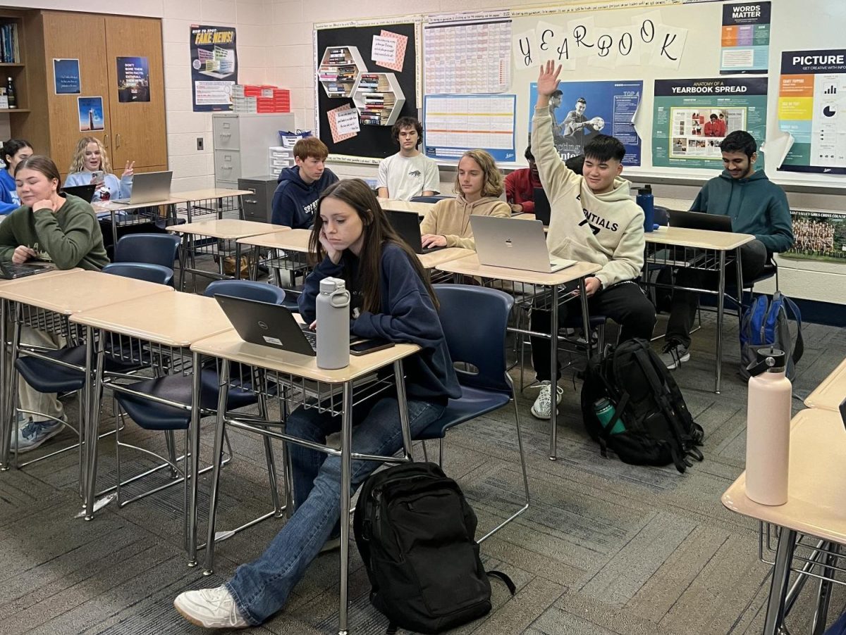 A student raises his hand to pitch a story in journalism class.