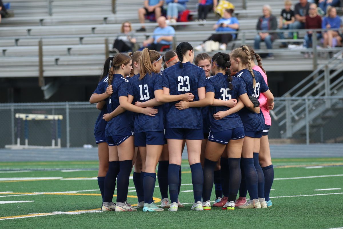 Girls varsity soccer team huddles before a game against Davenport North.